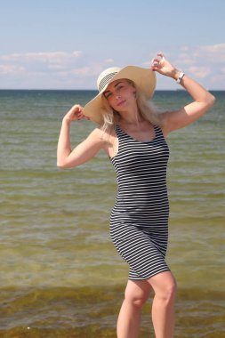 Denizin arka planında beyaz şapkalı bir kadın