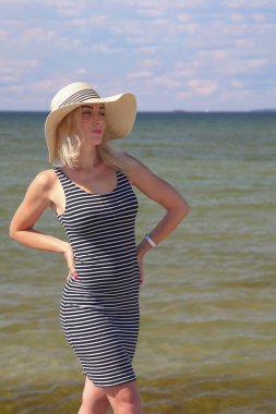 Denizin arka planında beyaz şapkalı bir kadın