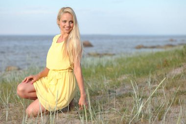 Yazın sarı elbiseli güzel bir kadın poz veriyor.