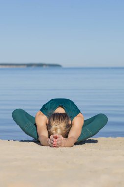 Genç güzel kız yazın deniz kenarında egzersiz yapıyor.