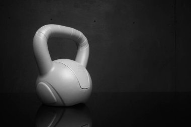 Siyah arka planda küçük plastik bir kettlebell.