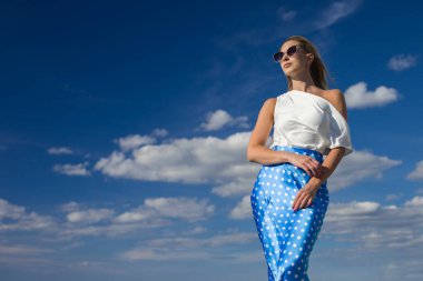 Deniz kenarındaki genç, narin kadın. Kıyafetler içinde poz veriyor.