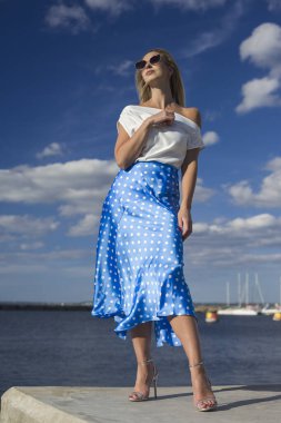 Deniz kenarındaki genç, narin kadın. Kıyafetler içinde poz veriyor.