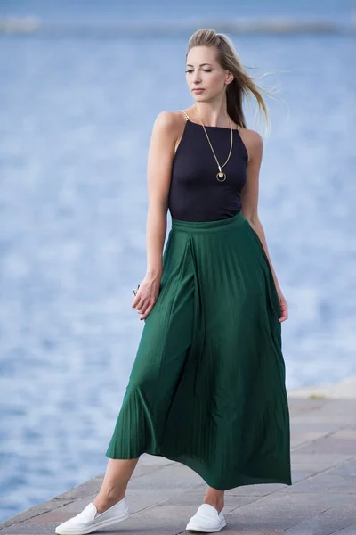 young slender woman by the sea posing in clothes