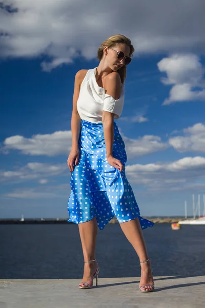 young slender woman by the sea posing in clothes