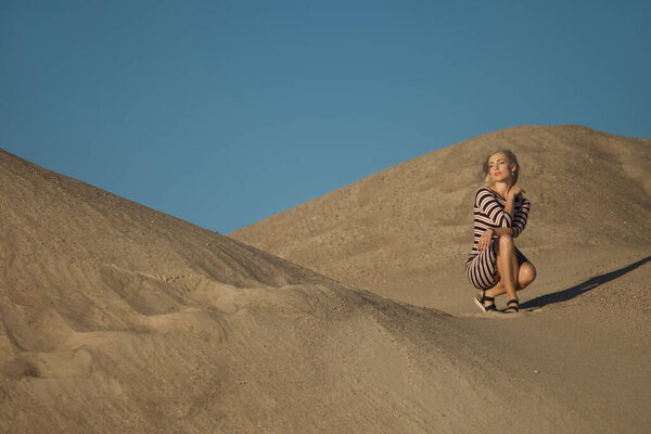 young woman on sandy mountain posing in dress