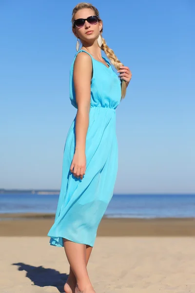 Menina em um vestido azul e óculos de sol no fundo do céu — Fotografia de Stock