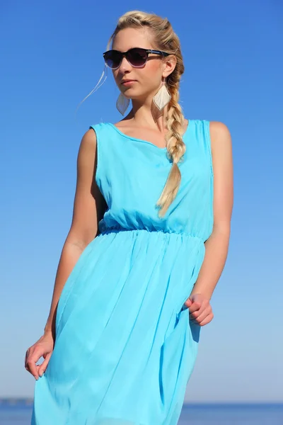 Menina em um vestido azul e óculos de sol no fundo do céu — Fotografia de Stock