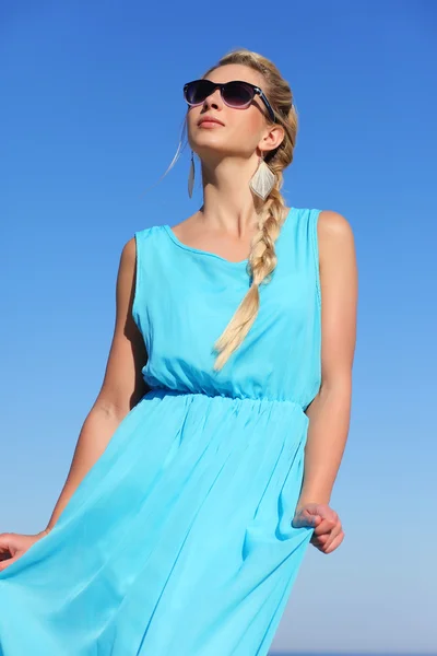 Chica en un vestido azul y gafas de sol en el fondo del cielo — Foto de Stock