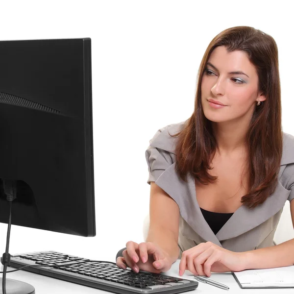 Menina atrás de uma mesa com um computador e um monitor — Fotografia de Stock