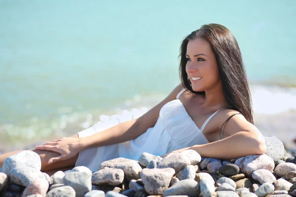 Giovane donna vestita di bianco sulle rocce in riva al mare — Foto Stock