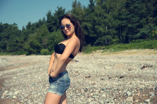 Vrouw in sexy korte broek die zich voordeed op strand — Stockfoto