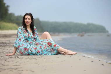 Sakin denizin kıyısındaki kumlu sahilde genç bir kadın