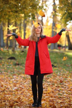 Parlak ceketli güzel bir kadın Sonbahar parkında yürüyüş yapıyor.