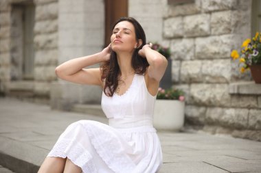 Beyaz elbiseli şık bir kadın Eski Avrupa sokaklarında yürüyor