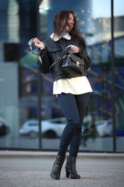 Moda kıyafetli gülümseyen kadın şehir ortamında neşeli poz veriyor.