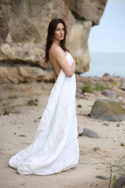 Huzurlu bir kadın kumsalda duruyor sakin doğal manzaranın tadını çıkarıyor.