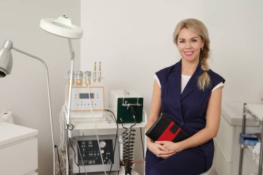 Kozmetik uzmanı modern estetik salonunda otururken notlar yazıyor.