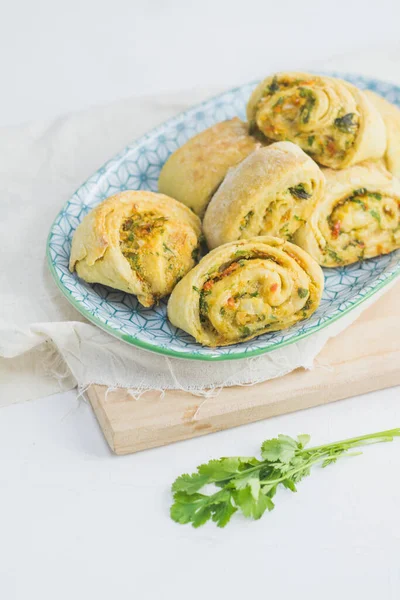 Home made buns with garlic, green parsley and sweet pepper in a plate with napkin and wooden cutting board white background. — Stock Image Home Made Buns Garlic Green Parsley Sweet Pepper Plate Napkin Royalty Free Stock Photos