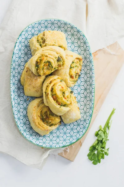 Home made buns with garlic, green parsley and sweet pepper in a plate with napkin and wooden cutting board white background. — Stock Image Home Made Buns Garlic Green Parsley Sweet Pepper Plate Napkin Stock Photo