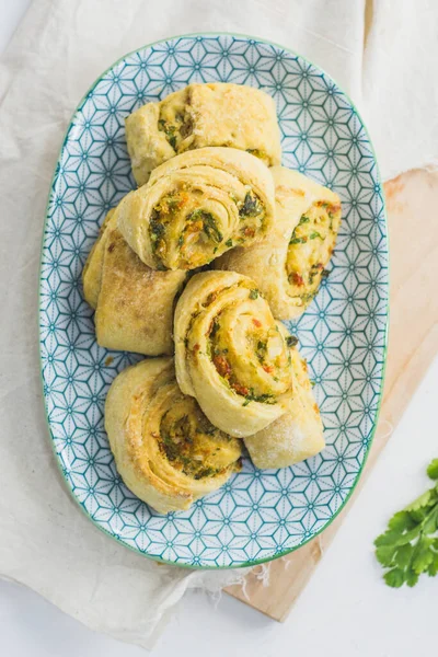 Home made buns with garlic, green parsley and sweet pepper in a plate with napkin and wooden cutting board white background. — Stock Image Home Made Buns Garlic Green Parsley Sweet Pepper Plate Napkin Stock Photo