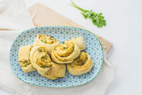 Home made buns with garlic, green parsley and sweet pepper in a plate with napkin and wooden cutting board white background. — Stock Image Home Made Buns Garlic Green Parsley Sweet Pepper Plate Napkin Royalty Free Stock Images