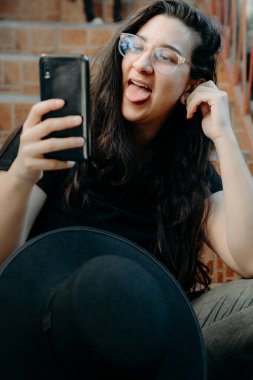 Cep telefonu kullanan, gözlüklü, siyah şapkalı bir kadının portresi..