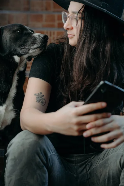 Gözlüklü, siyah şapkalı, yanında bir köpek olan bir kadının portresi..