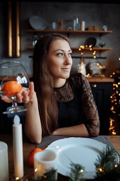 En vacker ung kvinna i svart klänning sitter vid bordet och håller en mataffär. — Stockfoto
