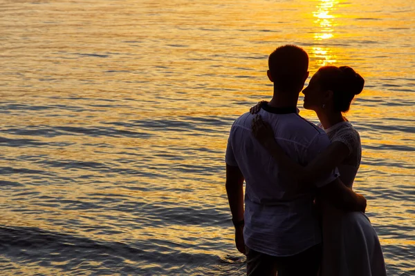 Silhouetten eines Mannes und einer jungen Frau am Meer. — Stockfoto