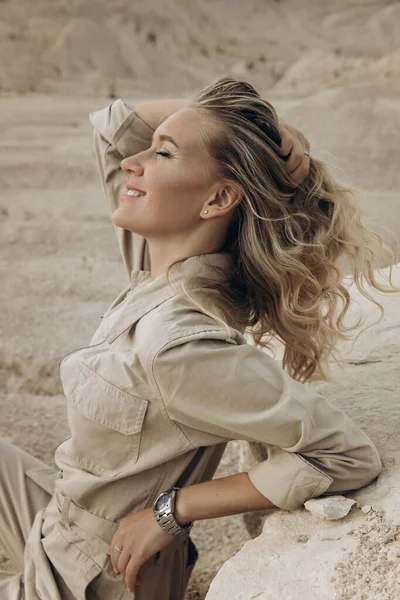 Çölde kumulların arasında bir kadın oturuyor..