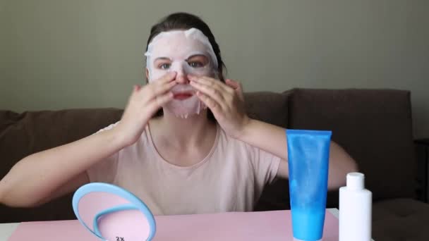 Una donna si siede a un tavolo e indossa una maschera di stoffa. — Video Stock