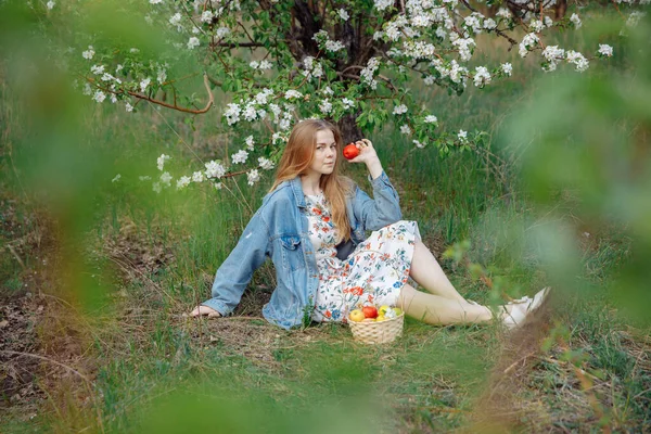 Mavi kot ceketli genç bir kadın açık bir alanda oturuyor.. 