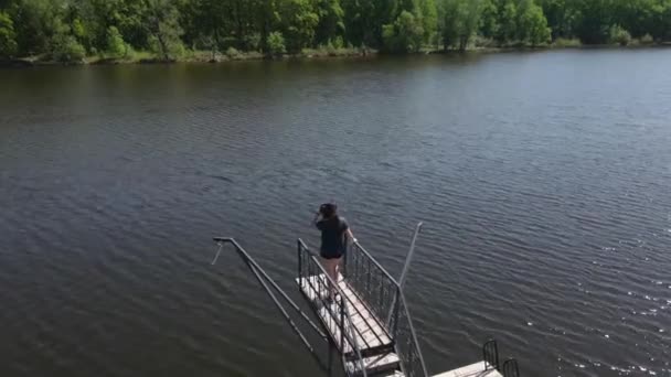 Una giovane donna sta sul molo e guarda l'acqua. — Video Stock