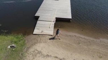 Kadın rıhtımdan çıkıp sobaya çıkıyor ve sahil boyunca yürüyor.. 