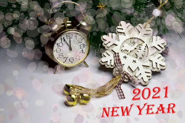 Yeni yıl saati ahşap parıltılı kar tanesiyle süslenmiş, bokeh efektli ve 2021 yılbaşı yazısıyla. Noel ve Yeni Yıl Kutlama Konsepti.