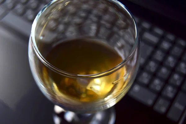 Laptop computer with glass of wine soft focus blurred background author's idea, search concept.