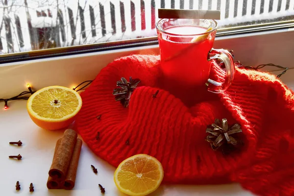 Glühwein mit Gewürzen und einem roten Schal auf einem hellen Fensterbrett. Weihnachtsurlaub und Wärmekonzept zu Hause. — Stockfoto