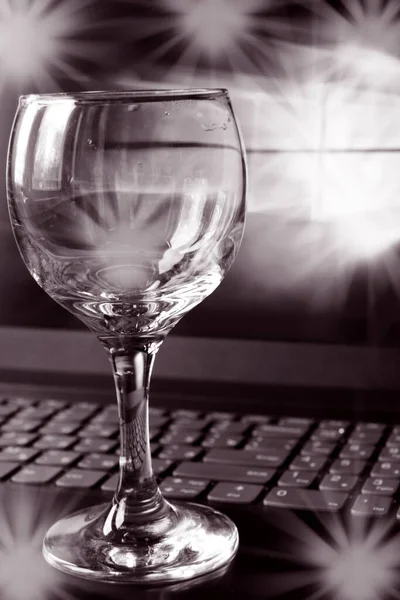 Black and white photo of one empty wine glass on a laptop keyboard with highlights Royalty Free Stock Photos