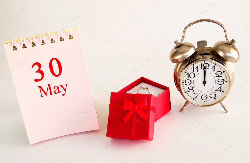 calendar date on light background with red gift box with ring and alarm clock with copy space. May 30 is the thirtieth day of the month.