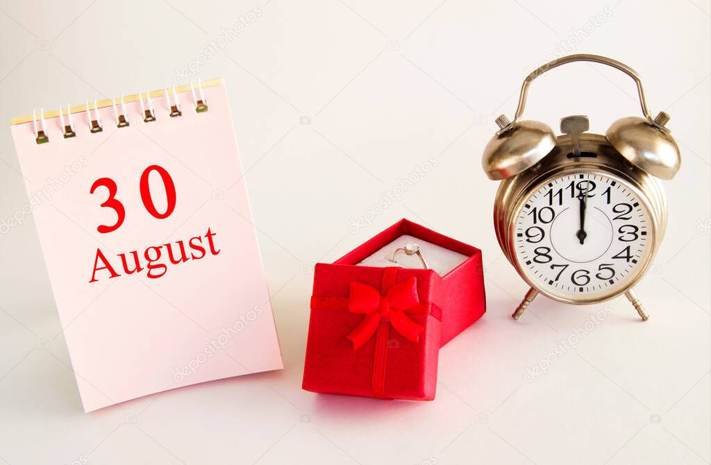 calendar date on light background with red gift box with ring and alarm clock with copy space. August 30 is the thirtieth day of the month.