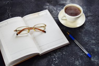 Uzak online çalışma, gözlüklü ve kalemli iş konsepti günlüğü, bir fincan sıcak çay..