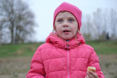 Küçük kız bir parça ekmek yiyor Göl kenarında doğal ışık, mutluluk güzel gözler