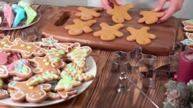 Bir kadın Noel kurabiyelerini renkli şekerle kaplamak için serer.