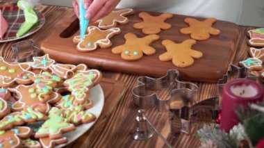 Bir kadın eli zencefilli çöreğin üzerine renkli şeker kreması sürüyor.