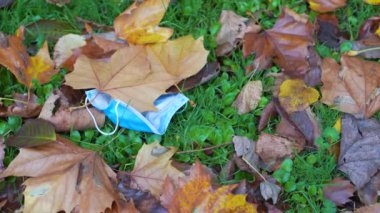 Düşen yaprakların üzerine atılmış tıbbi maske, yakın plan, kopyalama alanı, 4K