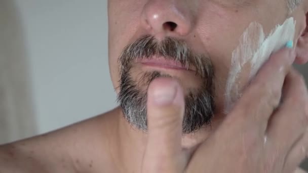 Närbild, smetar en medelålders man sitt ansikte med raklödder, 4K — Stockvideo