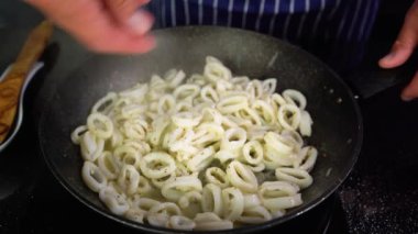 Bir adam tavada baharatlı kalamar halkaları pişiriyor, yakın plan, 4K