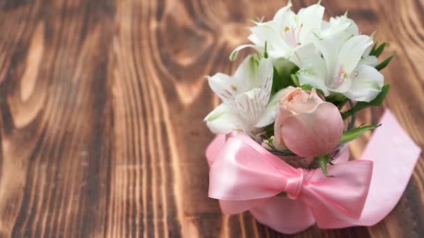Bukiet kwiatów z różową wstążką na drewnianym tle podczas śniegu — Wideo stockowe