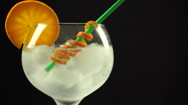 Cubos de hielo cayendo en gin cocktail naranja con paja, vídeo vertical 4k, primer plano — Vídeo de stock